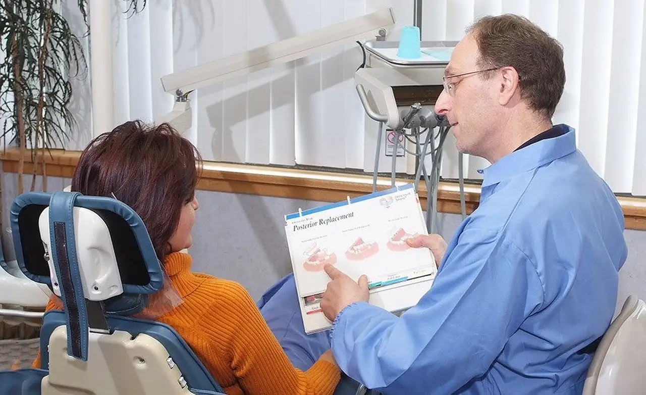 A treatment consultation in one of the practice's operatories, with a chart of tooth-replacement options in hand.